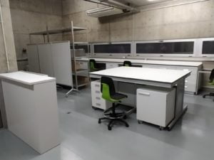 Vista de laboratorio que incluye módulo fregadero, isla, muebles y poyatas de laboratorio, así como taburetes Bimos Labsit de laboratorio.